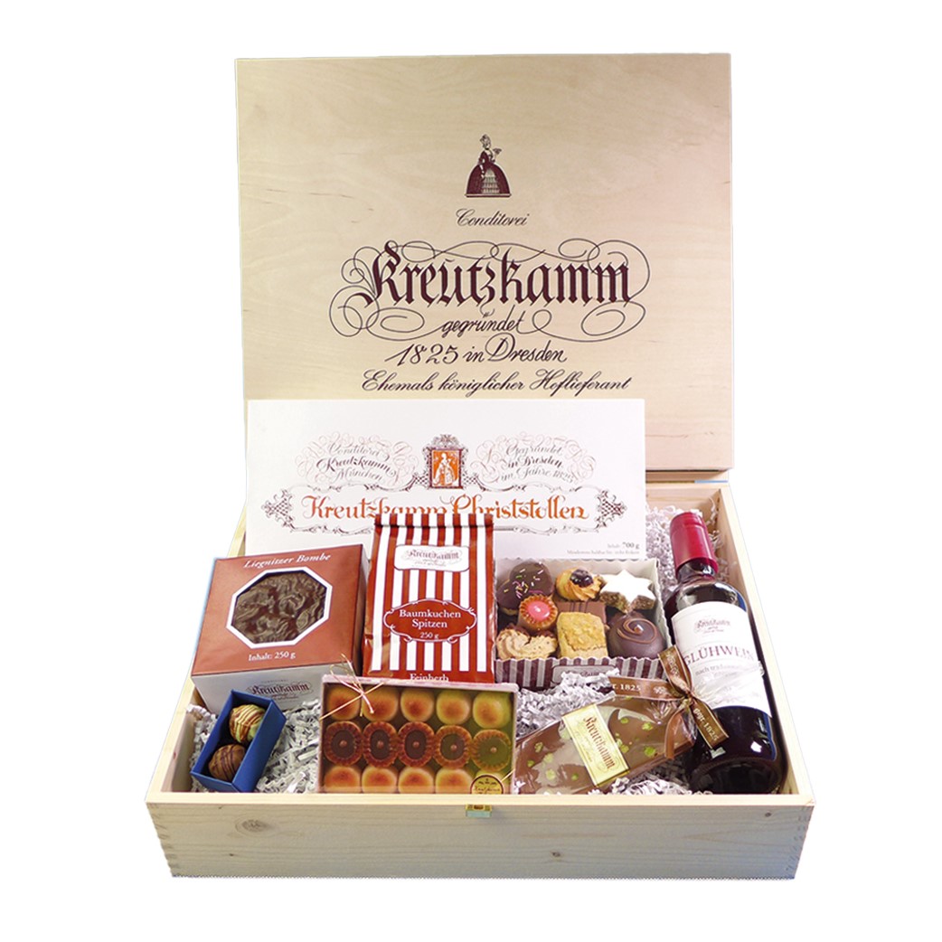 Holzkiste mit verschiedenen Suessigkeiten, Flasche Gluehwein; umgeben von Verpackungen. Text: "Conditorei Kreutzkamm gegruendet 1825 in Dresden Ehemals koeniglicher Hoflieferant Kreutzkamm Christstollen".