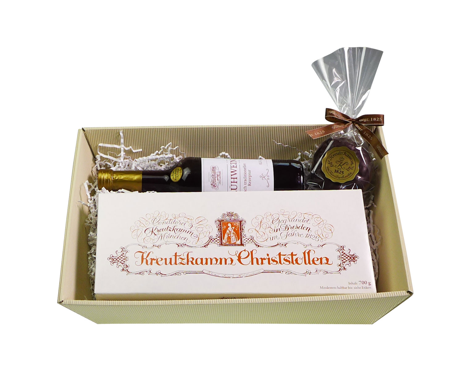Geschenkbox mit Kreutzkamm Christstollen, Flasche Gluehwein und verpacktem Gebaeck auf Fuellmaterial.