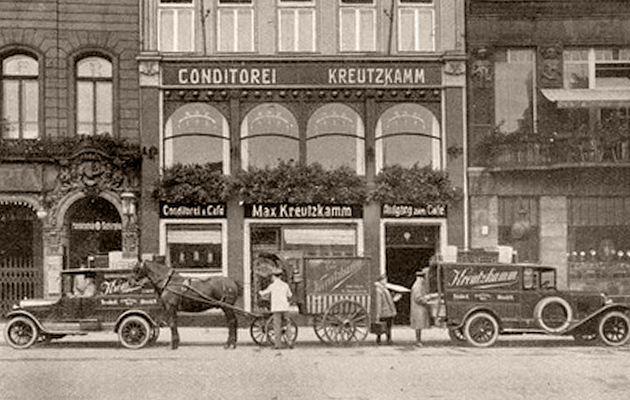 Pferdewarenwagen und Auto parken vor der Konditorei Max Kreutzkamm. Beschriftung: 
