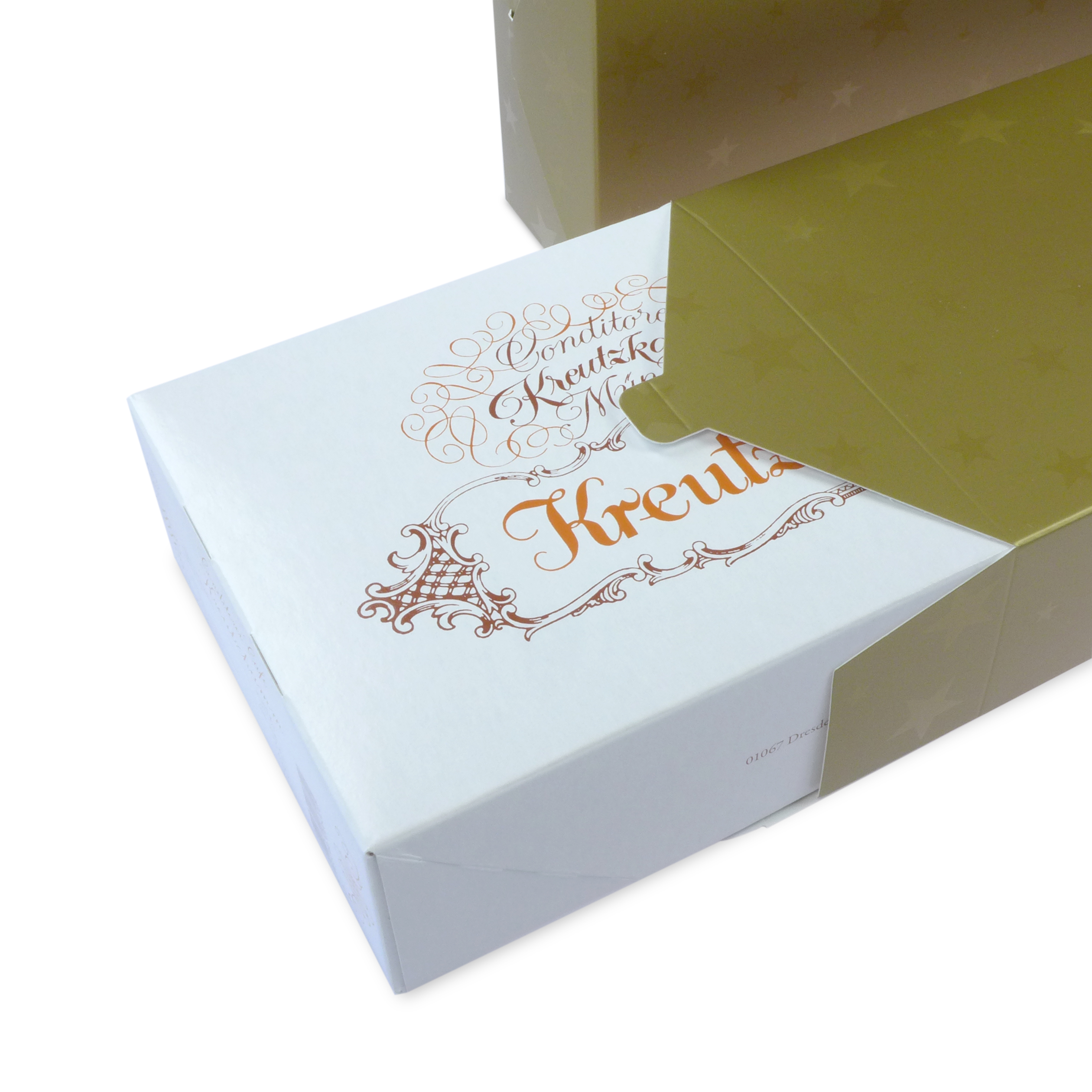 Kartonbox mit der Aufschrift "Backhaus Kreutzkamm" in festlichem Design, teils in goldener Verpackung.