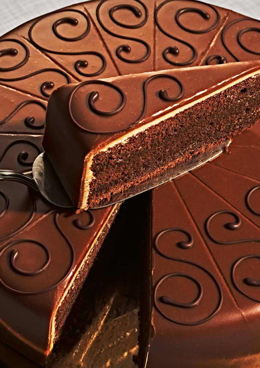 Ein Schokoladenkuchen wird geschnitten. Spiralmuster verzieren die Oberseite des Kuchens.